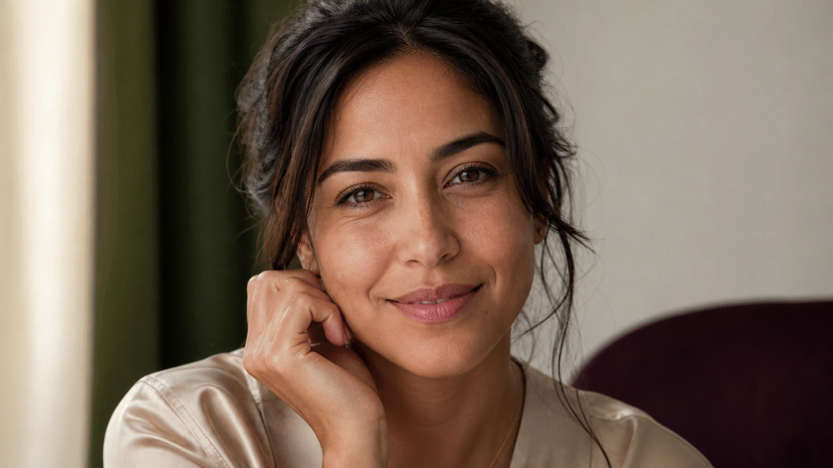 Smiling Latina woman with natural under-eye movement lines and skin texture in soft daylight.