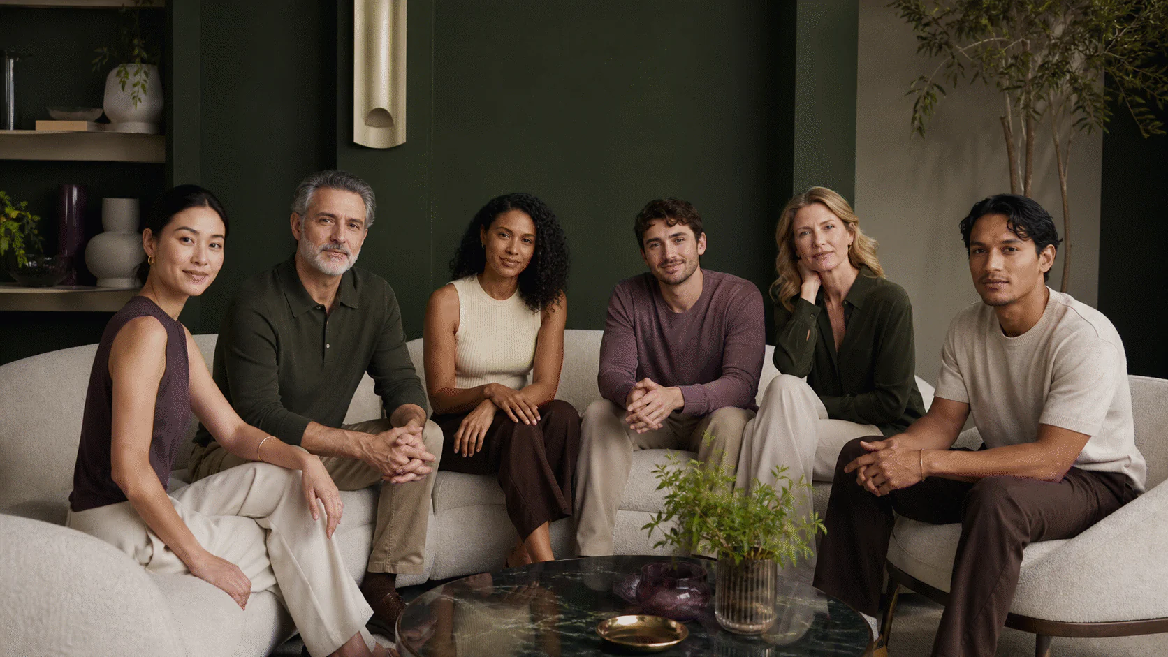 Six diverse adult cosmetic-study volunteers seated together in a refined green and pearl room.